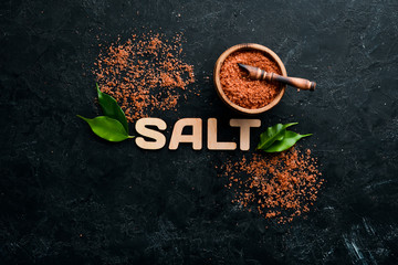 Brown Sea salt with the inscription SALT. On a black stone background. Spa treatments. Top view. Free copy space.