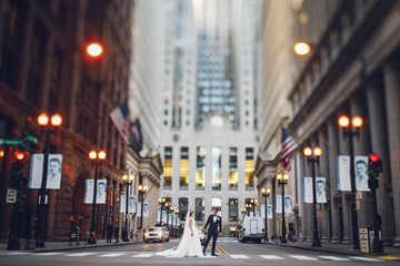 Elegant bride in a white dress and veil. Handsome groom in a blue suit. Couple in a big city