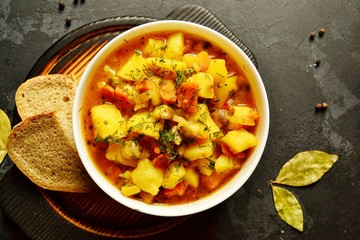 Vegetable stew in a white bowl on a dark wooden background. A dish of potatoes. Appetizing hot food, with vegetables. Vegetable Vegetarian Stew. Bowl with potatoes on a wooden board for serving dishes