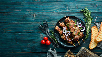 Juicy skewers of meat in a black plate. Barbecue, kebab. Top view. Free copy space.
