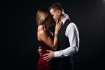 passionate man and woman hugging , kissing during the party. close up side view photo, isolated balck background, studio shot