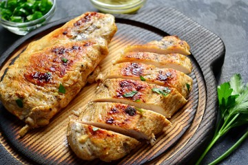 Grilled chicken breast. Chicken fillet with broccoli and mushrooms. Appetizing chicken meat on a wooden board on a dark background