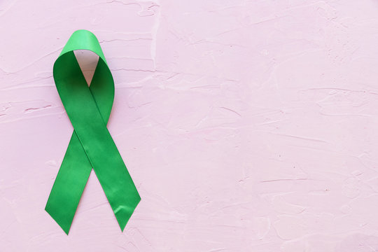 Mental health awareness green ribbon on pink backdrop