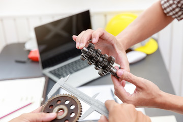Engineer discussing and designing about mechanical gear parts in office.