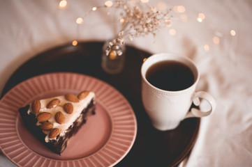 Tasty chocolate cake with almond nuts and cup of tea over light at background. Breakfast time.