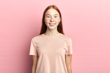 Obraz premium Portrait of nice glad cheerful girl in casual pink t-shirt, looking at the camera , isolated over pink background. close up portrait, studio shot. beauty, people, youth concept