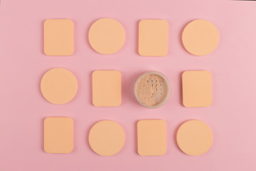 A lot of sponge, a beautiful blender for applying foundation or powder. Flat lay on a pink background, copy space.