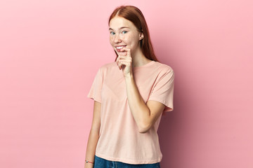 cheerful woman touching her lips while thinking, isolated pink studio background. close up side...