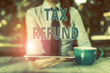 Handwriting text Tax Refund. Conceptual photo refund on tax when the tax liability is less than the tax paid Business woman sitting by the table with cup of coffee and mobile phone