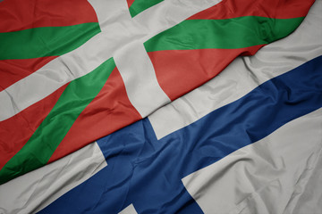 waving colorful flag of finland and national flag of basque country.