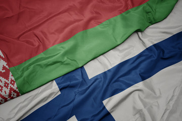 waving colorful flag of finland and national flag of belarus.