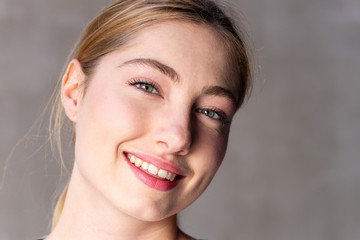Naklejka premium Close up smiling beautiful blond girl by gray all