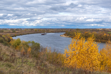 cargo ship floating on the river on the background of a beautiful autumn landscape