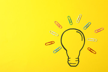 Drawn light bulb and clips on yellow background. Good idea concept