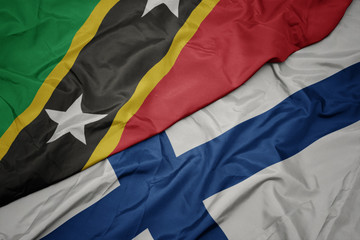waving colorful flag of finland and national flag of saint kitts and nevis.