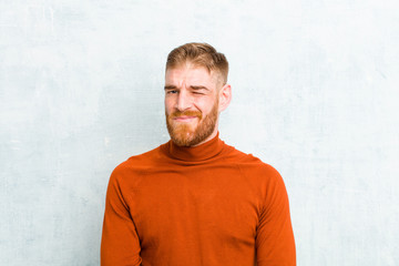 young red head man wearing turtle neck looking happy and friendly, smiling and winking an eye at...