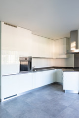 Modern white kitchen in empty apartment with white walls