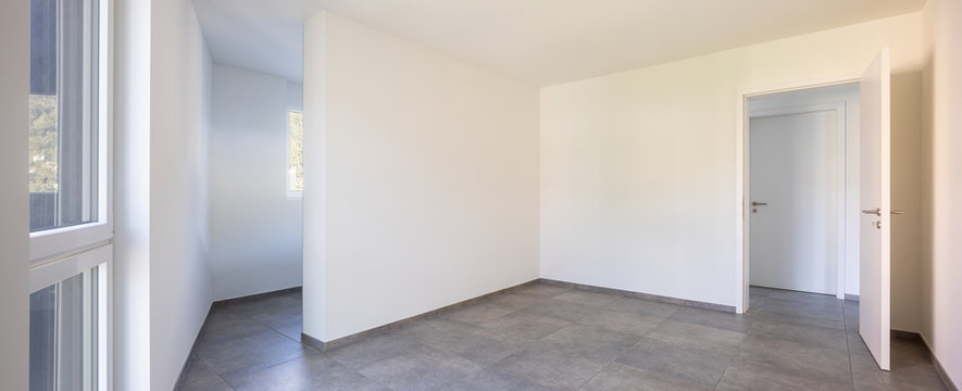 Empty room with white walls, open door and access to the room's private bathroom