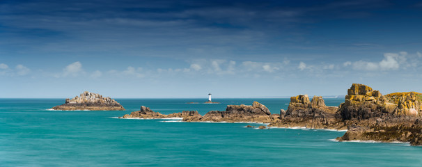 view of the rocks and reefs on the Normandy coast at low tide with the Pierre de Herpin lighthouse