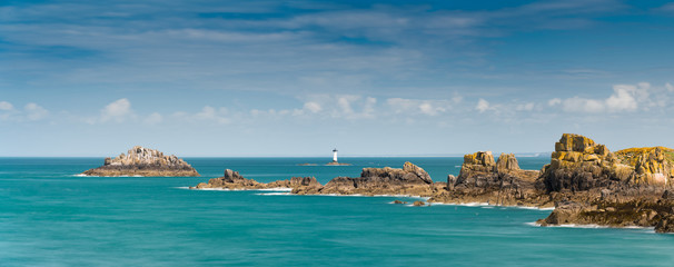 view of the rocks and reefs on the Normandy coast at low tide with the Pierre de Herpin lighthouse - obrazy, fototapety, plakaty