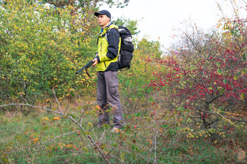 man with semi-automatic shotgun and backpack is hunting in the autumn forest