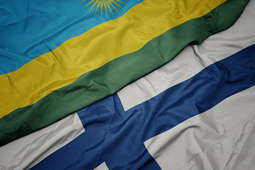 waving colorful flag of finland and national flag of rwanda.