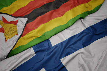 waving colorful flag of finland and national flag of zimbabwe.