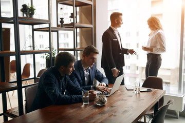 Group of clever talented business people planning work in office, sharing ideas, thoughts indoors. close up photo. two people are standing in front of the window and talking