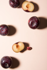 Plums and half plums on pastel background. Top view shot, abstract conception.