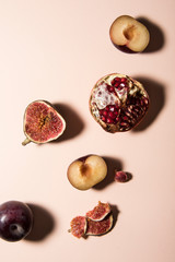 Plum, fig and pomegranate slices on pastel background. Top view shot, abstract food conception.