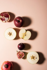 Four different kind of fruits on pastel background. Figs, plum, apple and pomegranate. Top view shot. Abstract food conception.