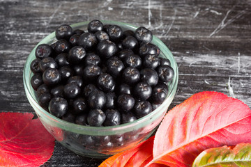 Close up chokeberries in glass bowl on black background