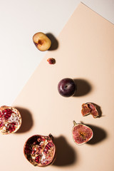 Three different kind of fruits on divided background. Figs, plum and pomegranate. Top view shot, abstract food conception.
