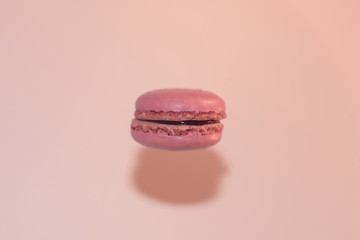Flying rose macaron as an ufo with shadow on the wall