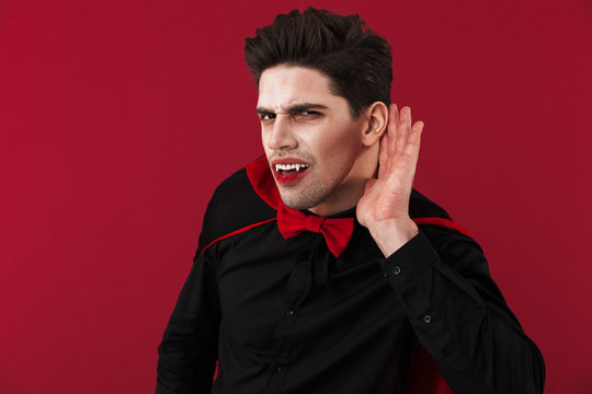 Image of vampire man in halloween costume listening with hand at his ear