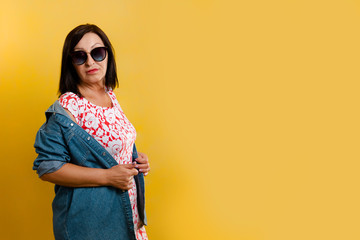 Women and advertising. Mature brunette woman in glasses and a denim shirt draped over her shoulder,...