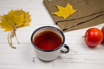 tea in a white cup with white sugar in cubes and cane sugar, maple leaves and apples on a wooden...
