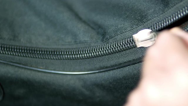 Zips the zipper of black bag