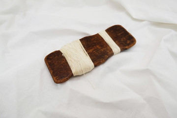 Dark Brown Wooden Spool On The White Cotton Fabric Background