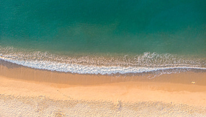 Aerial top view on the sandy beach. Umbrellas, sand, bridge and sea waves landscape.