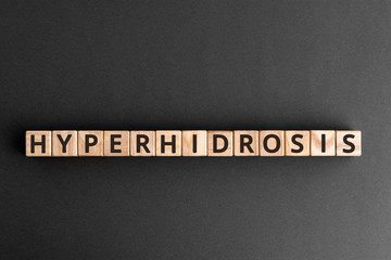 Hyperhidrosis - word from wooden blocks with letters, excessive sweating hyperhidrosis concept,  top view on grey background - obrazy, fototapety, plakaty