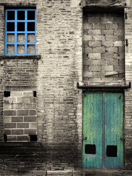 vintage style colorized image of an abandoned industrial warehouse and factory building with blue windows and green door