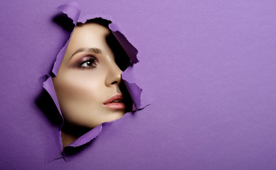 woman looks in hole colored purple paper, fashion beauty makeup and cosmetics, beauty salon