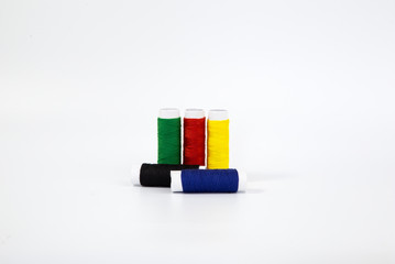 Threads of different colors with the coils in a row and swing needle on white background.