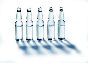 A row of clear glass ampules in bright light.