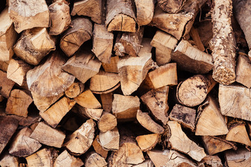 Close-up wooden logs folded in the form of woodpile lie on the street. Concept of rustic background and country life