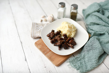 Sesame beef dish on a white wood background served with mashed potatoes and seasonings