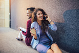 Young entrepreneurs sitting down in front of a modern office building and using phone. Brainstorming outside in a beautiful day.