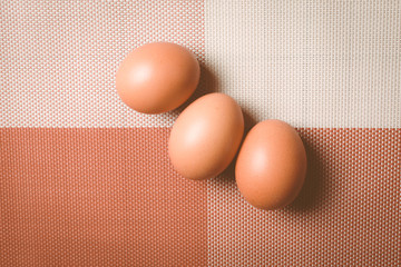 Three yellow eggs on a beautiful tablecloth.