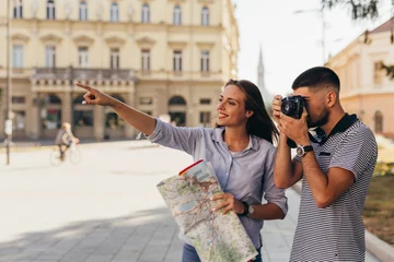 Foto op Canvas couple tourist in sightseeing in city using paper map and taking pictures with camera © cherryandbees